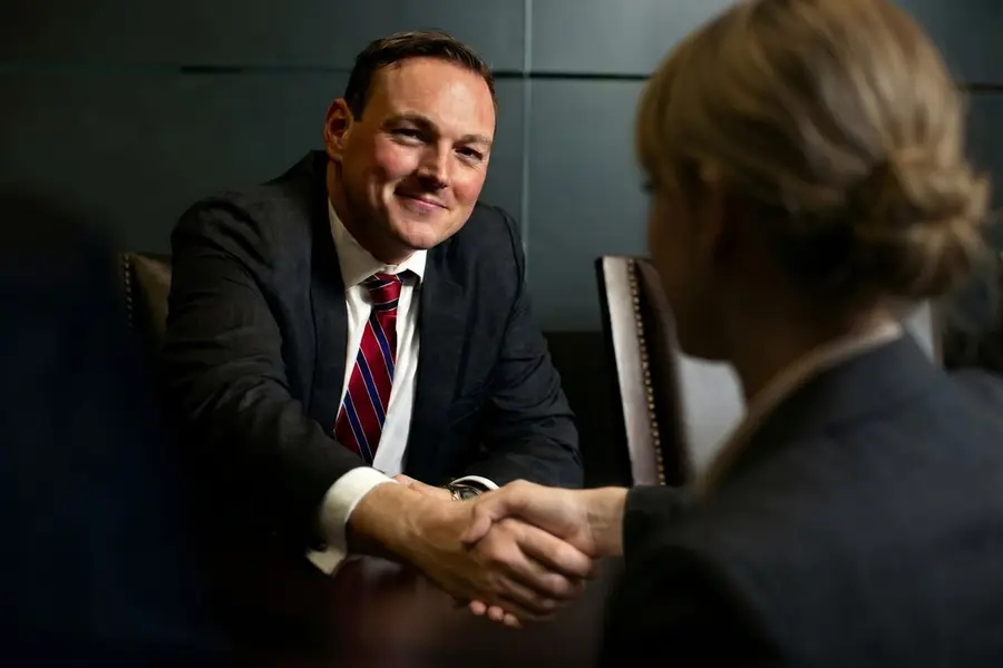 Erik Mitbrodt smiling and shaking hands across a boardroom table